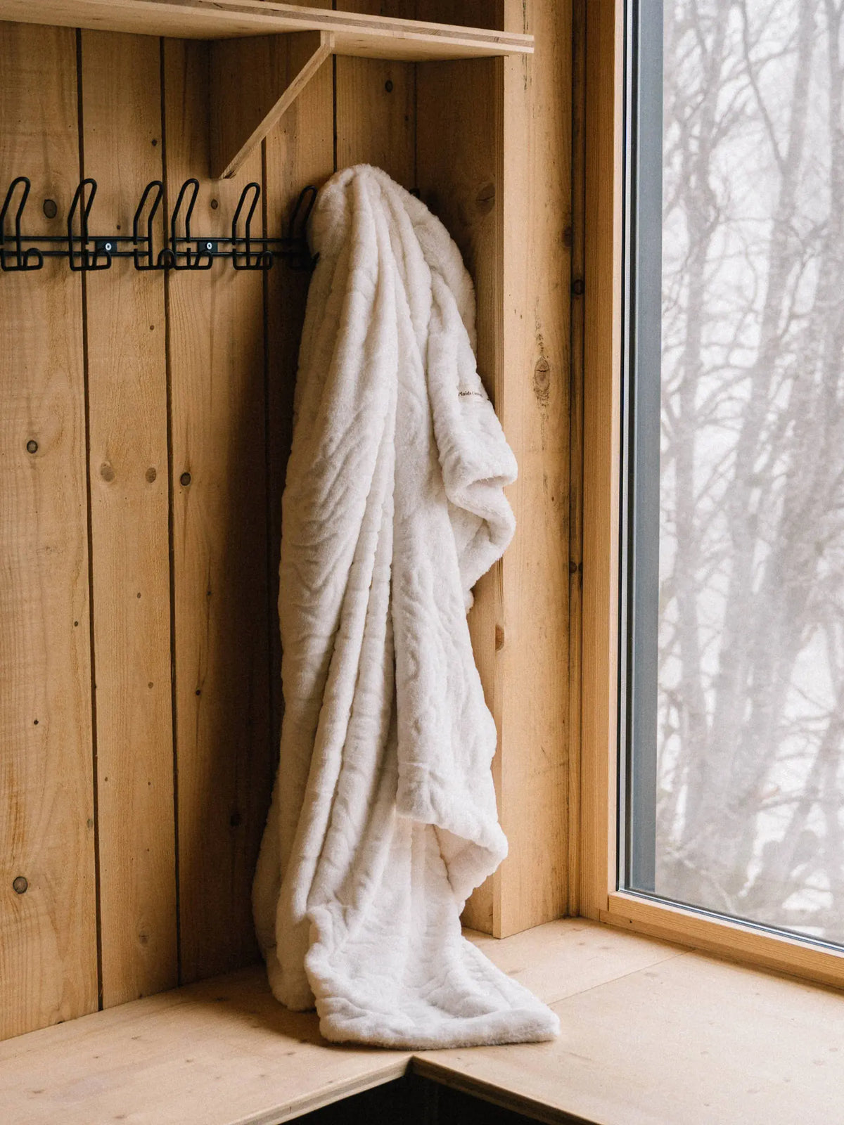 Plaid Ours Polaire Blanc accroché dans un chalet